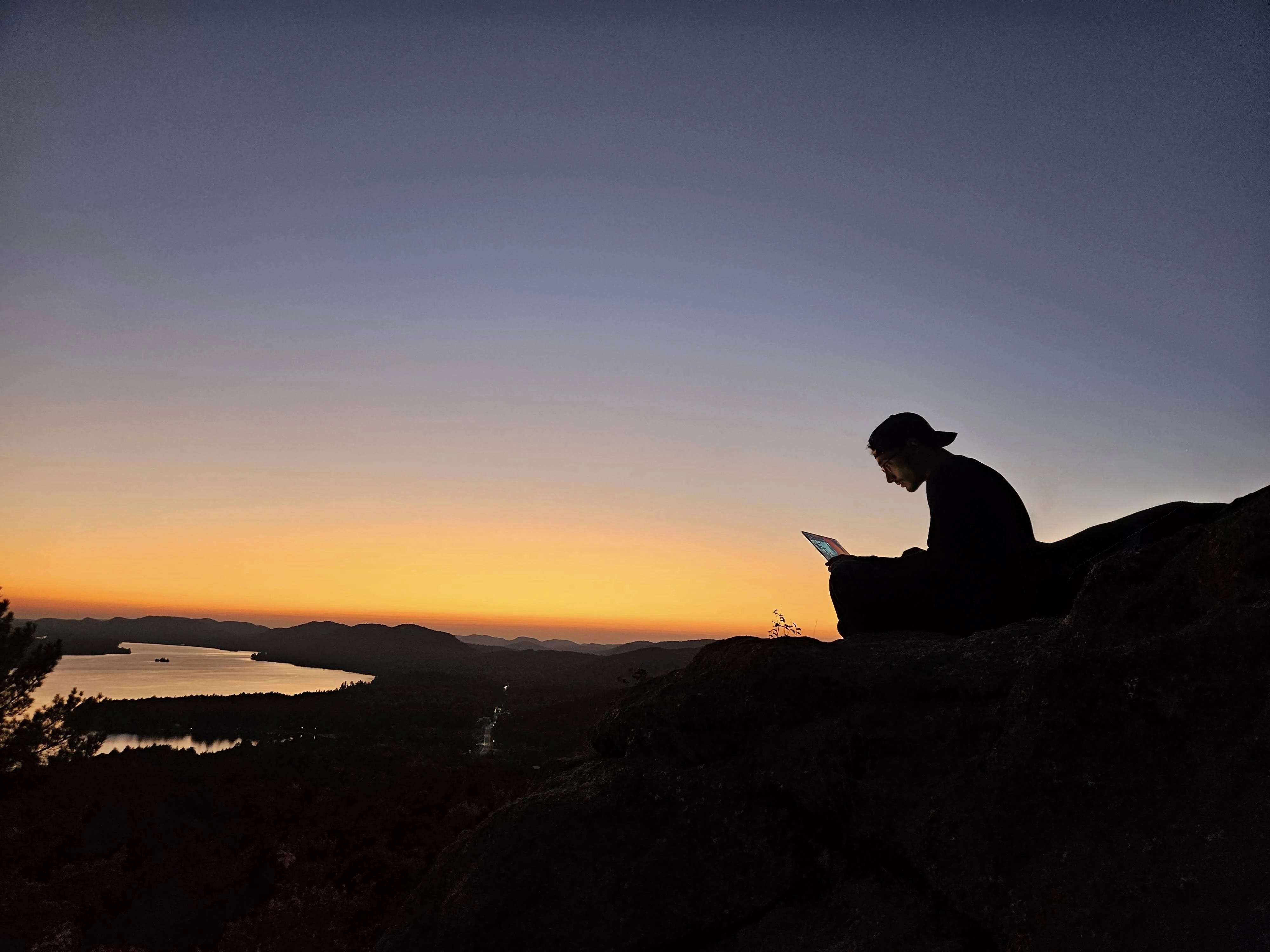 Sonny Cirasuolo silhouetted against a sunset, working on a laptop